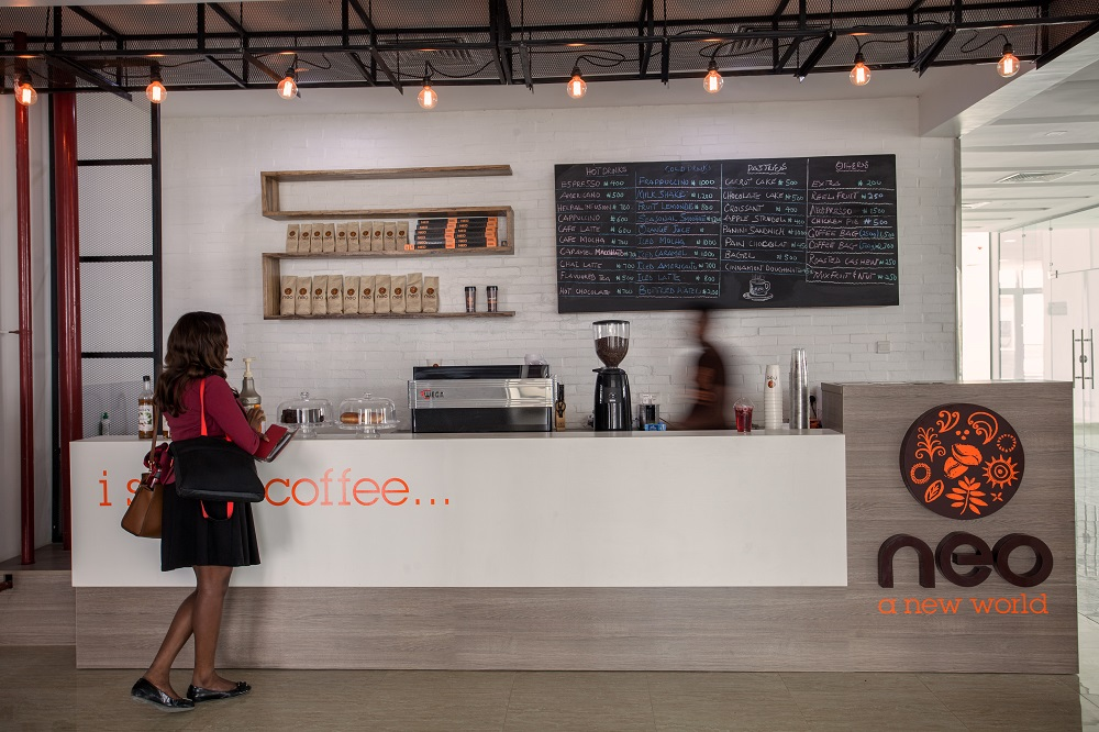 A cozy café in Lagos featuring a steaming cup of coffee on a wooden table.